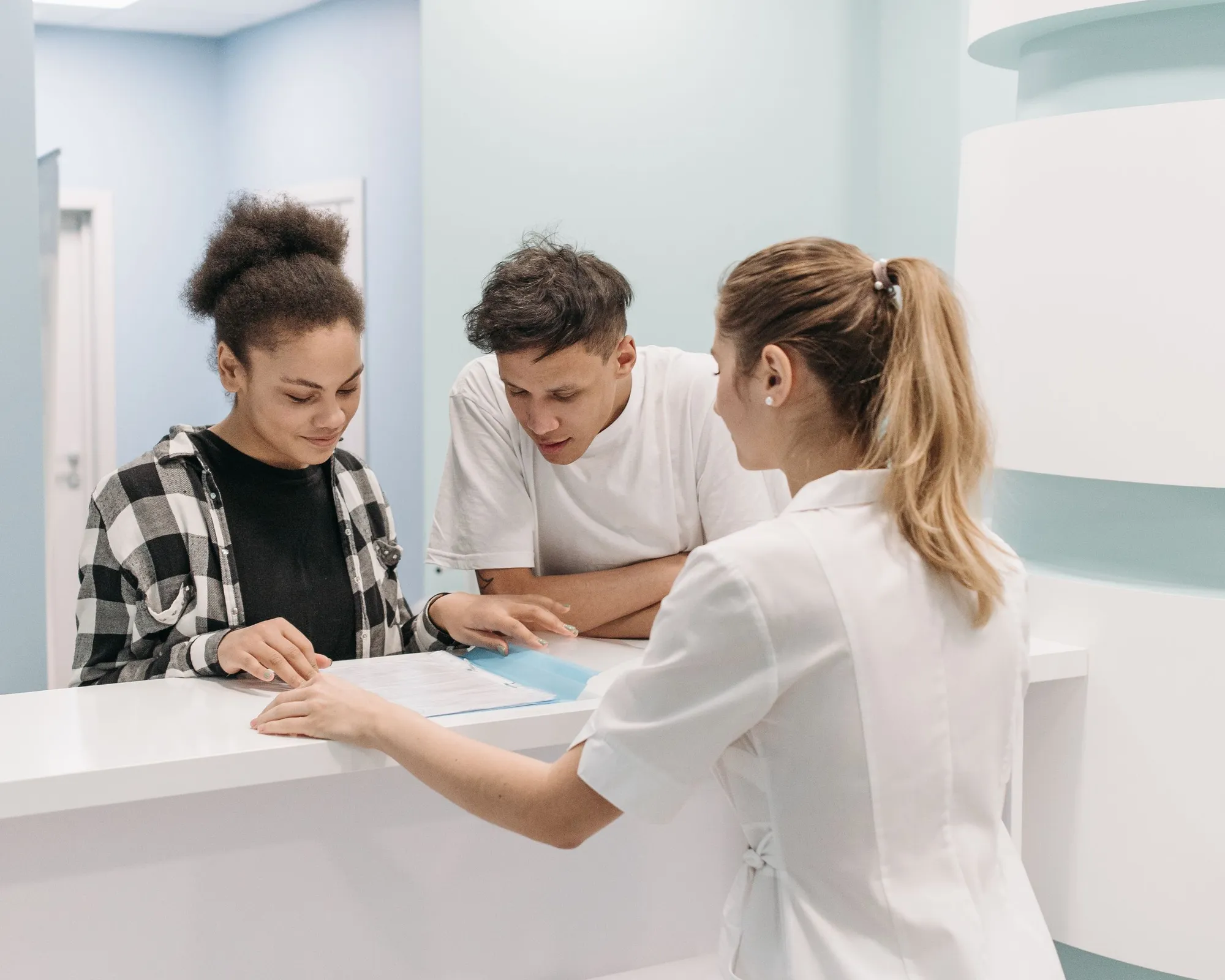 Patients in a modern clinic waiting area viewing healthcare practice information